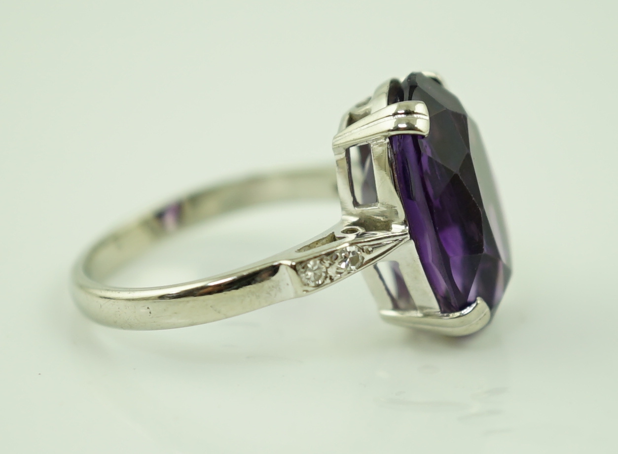 An 18ct white gold and oval cut amethyst set ring, with two stone diamond chip set shoulders